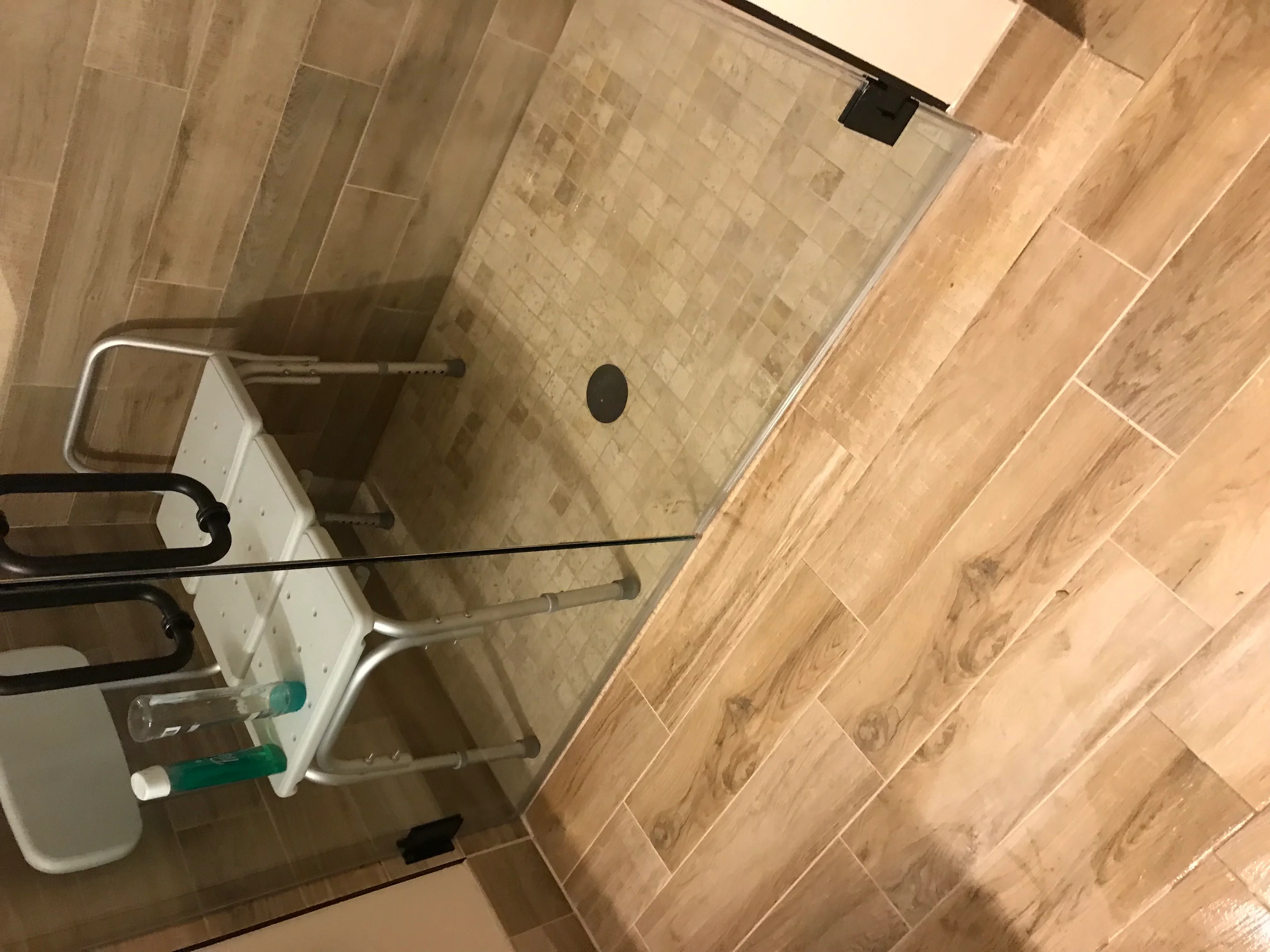 Modern bathroom with herringbone wood-look tile floor and subway tile shower with glass enclosure