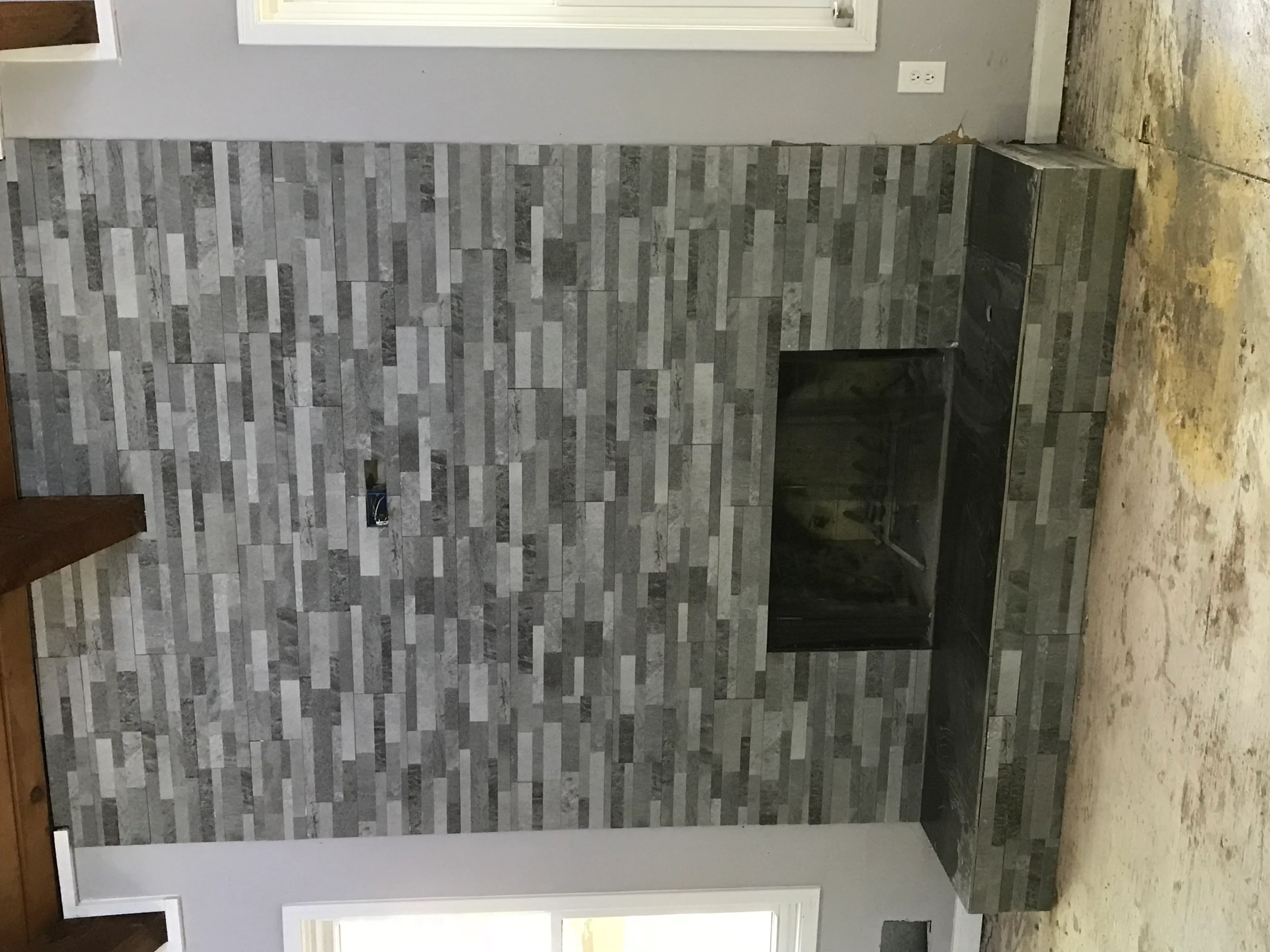 Gray and white vertical stacked stone tile shower with frameless glass door in bathroom