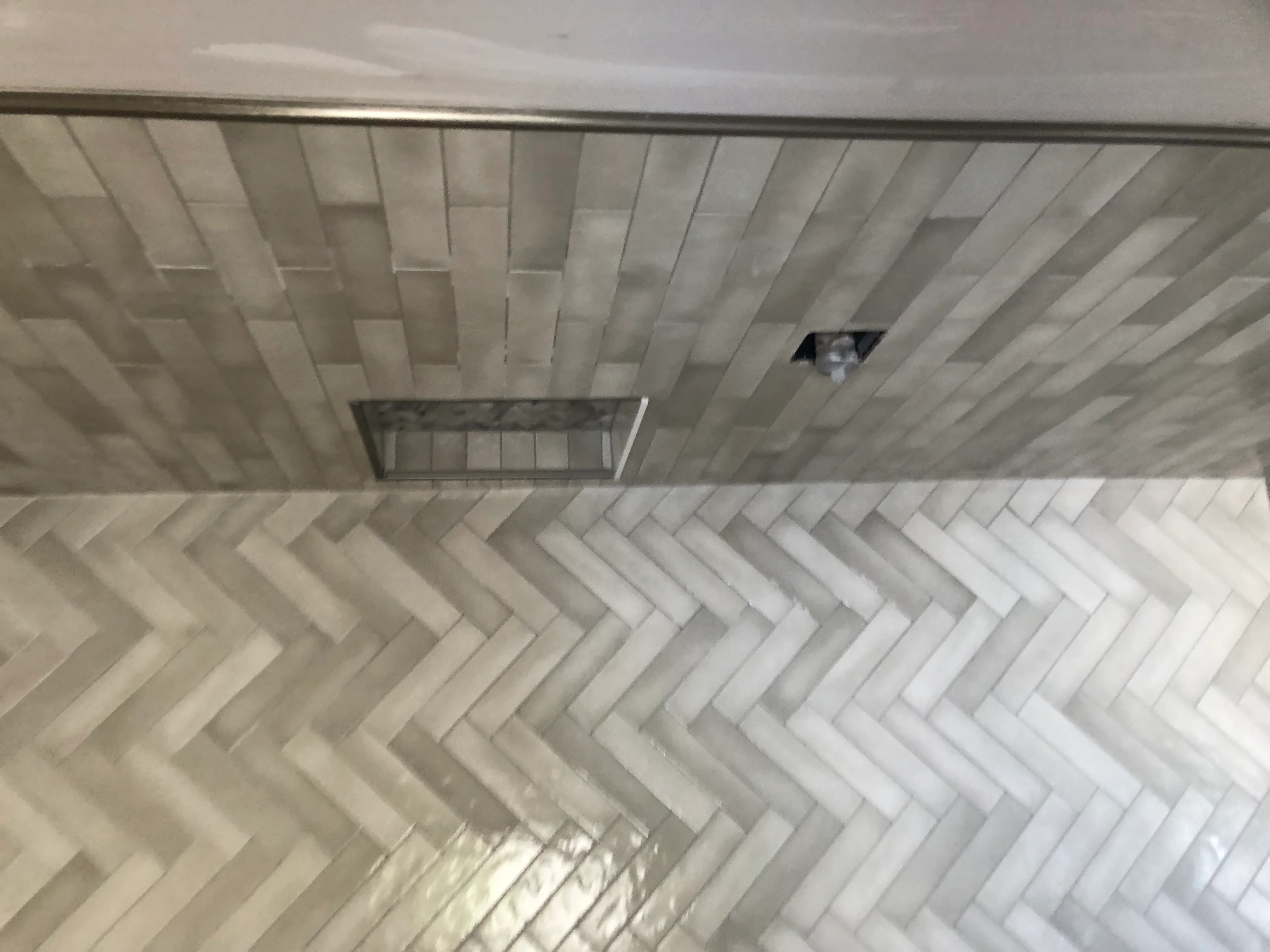 Overhead view of herringbone pattern tile ceiling with recessed lighting and ventilation