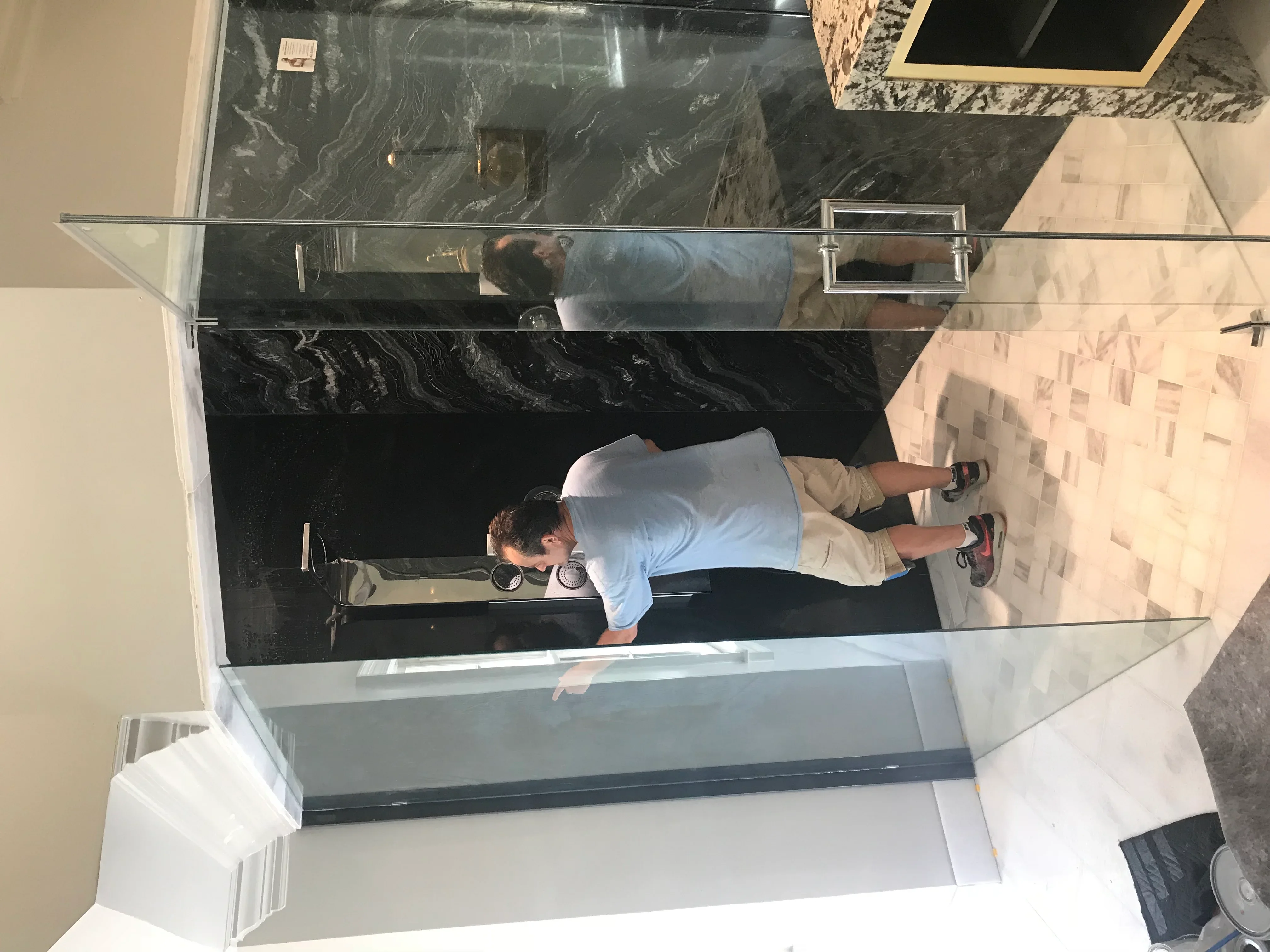 Bathroom remodel with black marble flooring, glass shower enclosure, and chrome fixtures