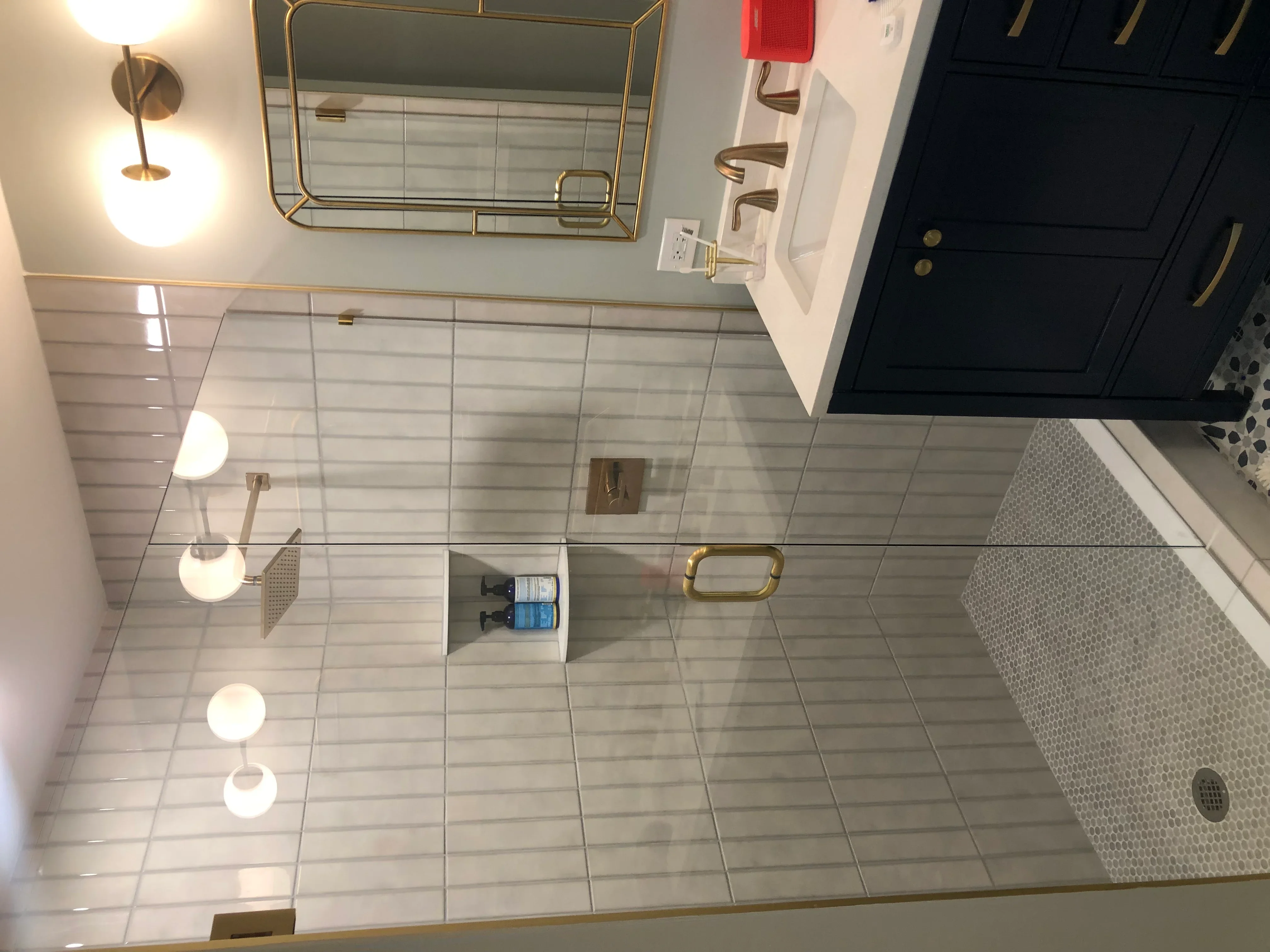 Modern bathroom with gray linear tile floor, frameless glass shower, and brass fixtures