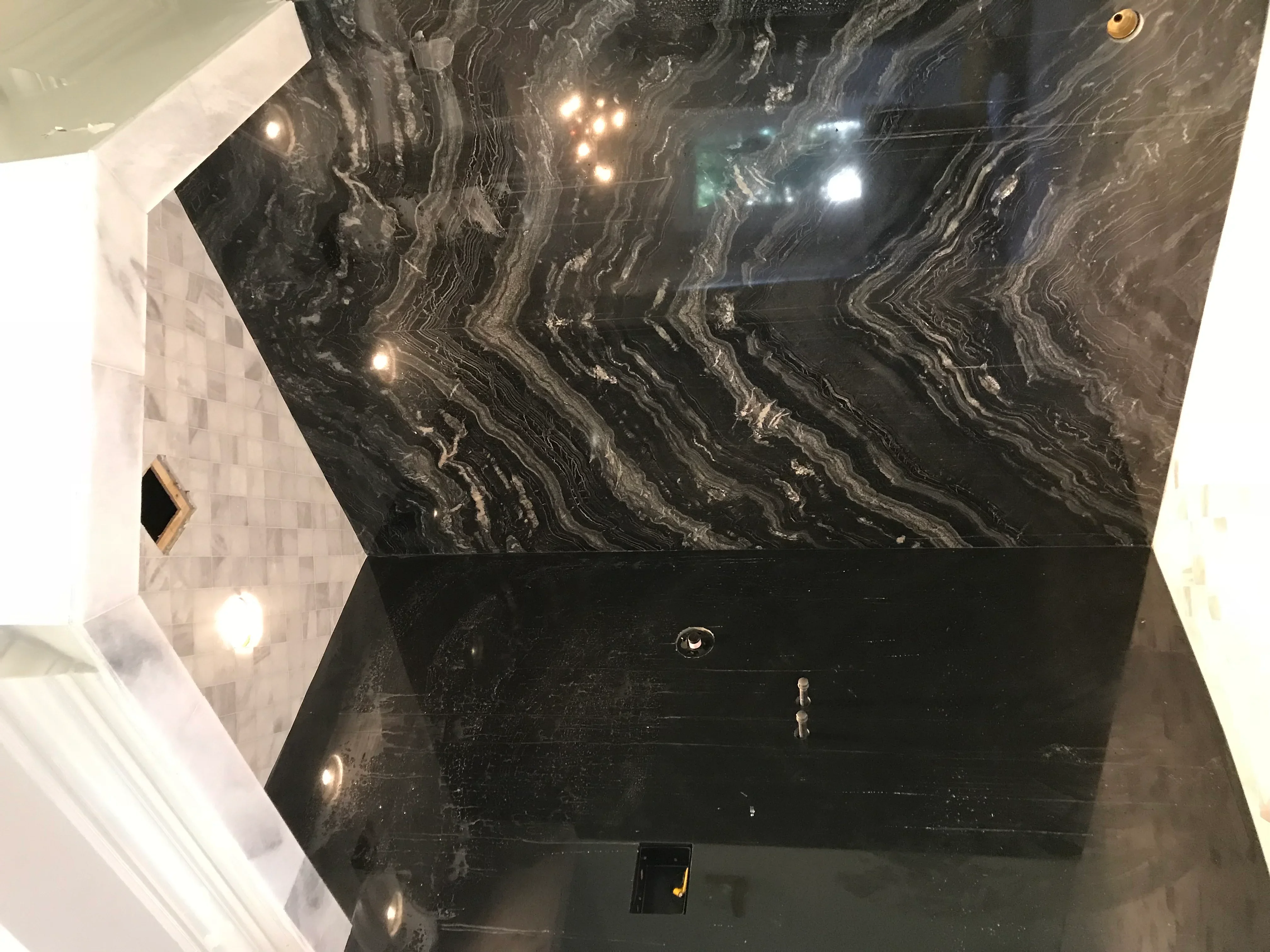 Black marble ceiling with gray veining and recessed lighting in luxury bathroom