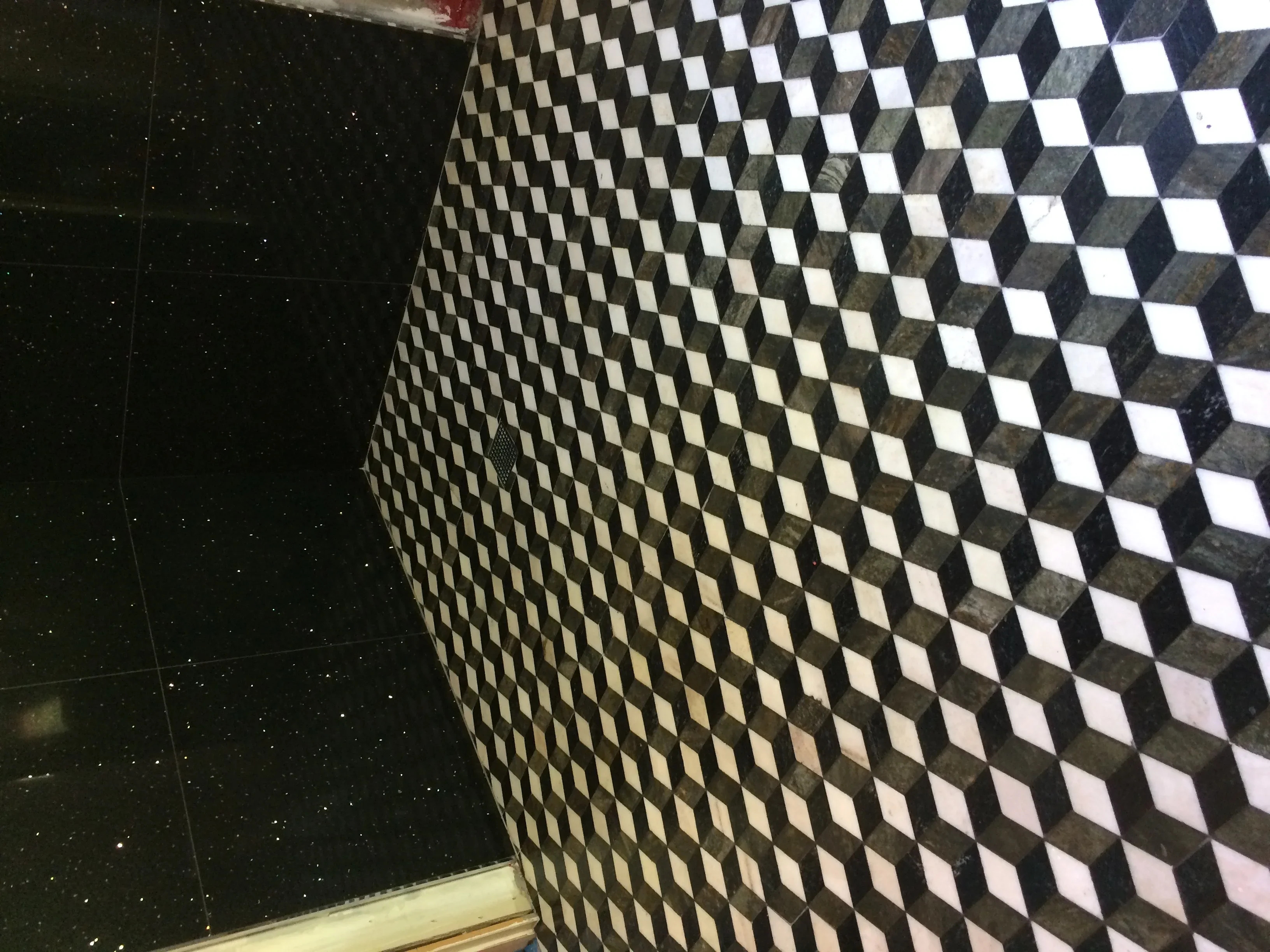 Black and white 3D geometric tile pattern on bathroom shower wall with dimensional cube design