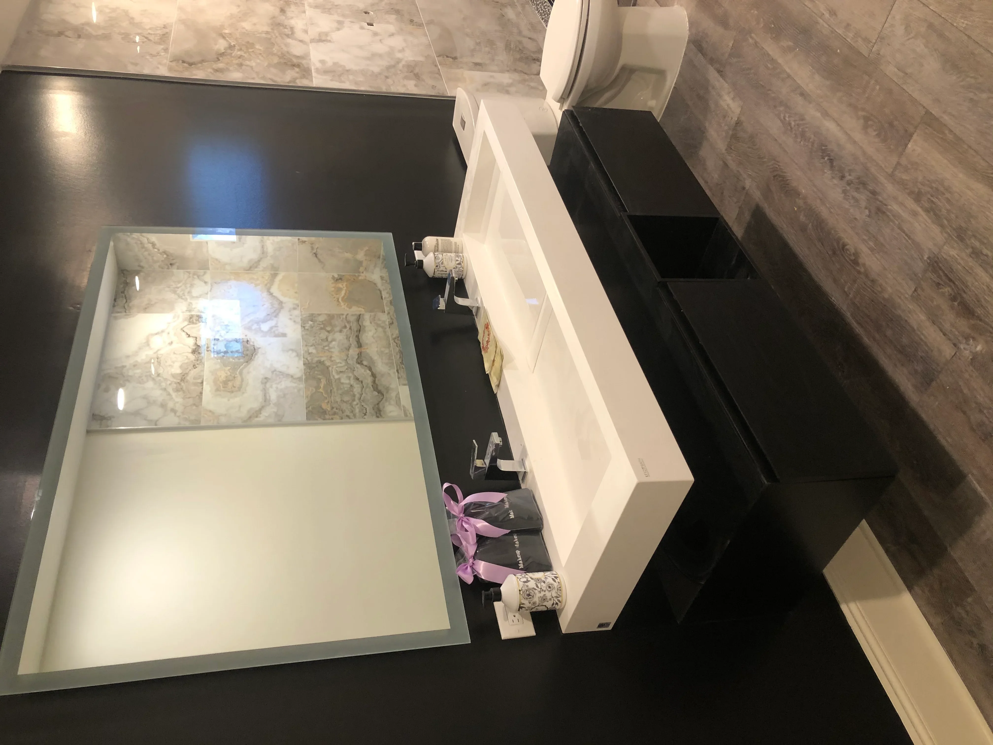 Modern bathroom with marble tile flooring, white vanity, and black storage cabinetry