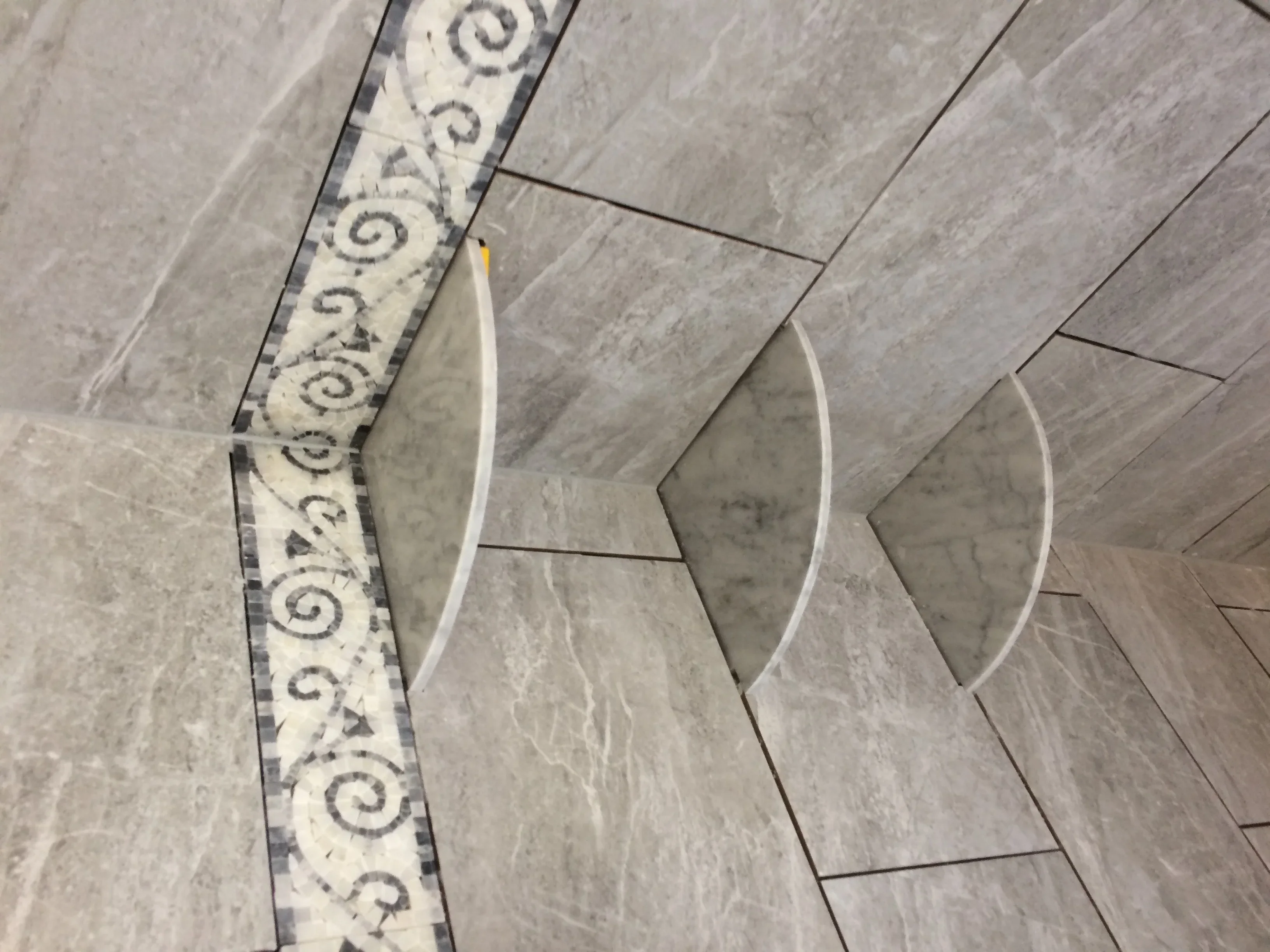 Gray marble bathroom floor tiles with ornamental scroll-pattern border detail